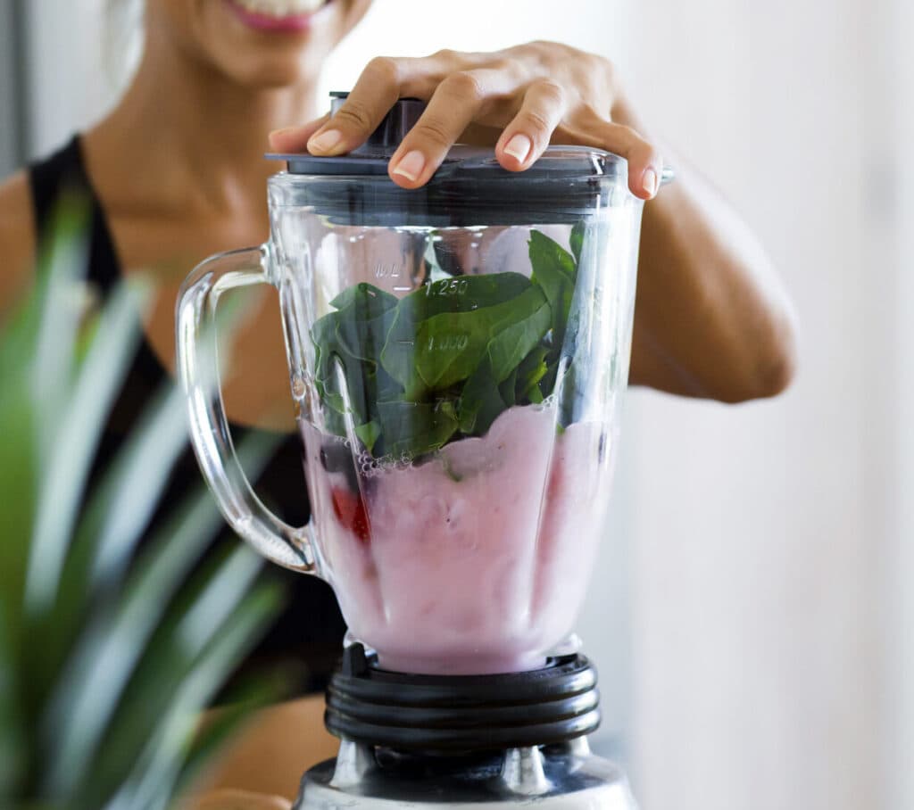 Woman blending a healthy green smoothie.