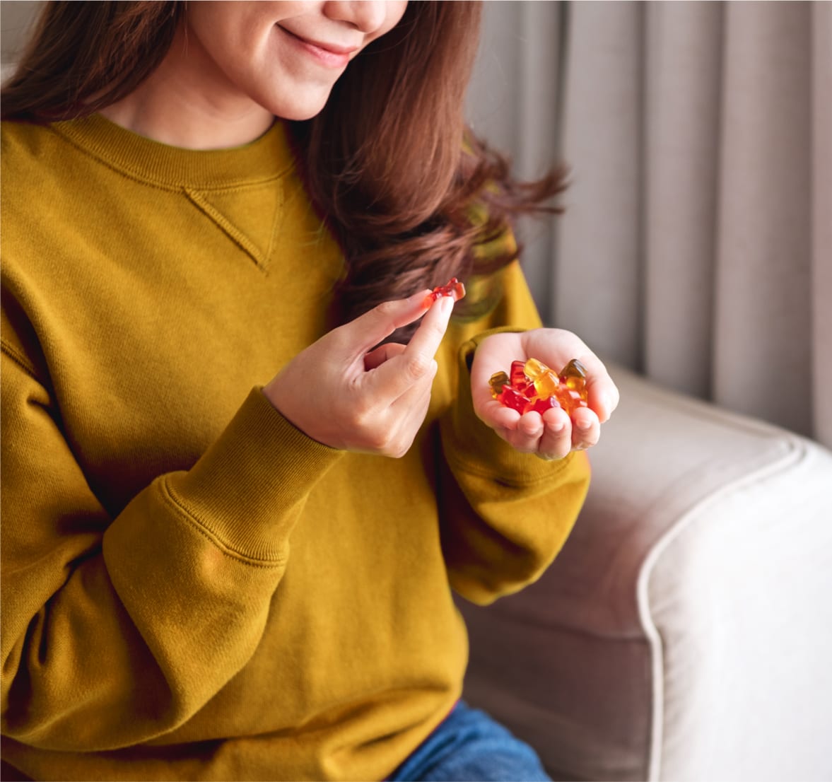 Closeup image of a young woman holding and eating vitamin gummies.