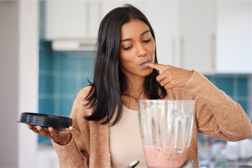 Young woman preparing a healthy smoothie at home.