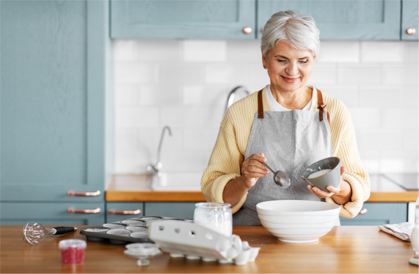 Older woman baking in home kitchen.