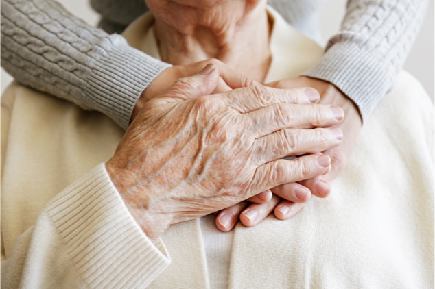 Mature female in elderly care facility gets help from a hospital personnel nurse.