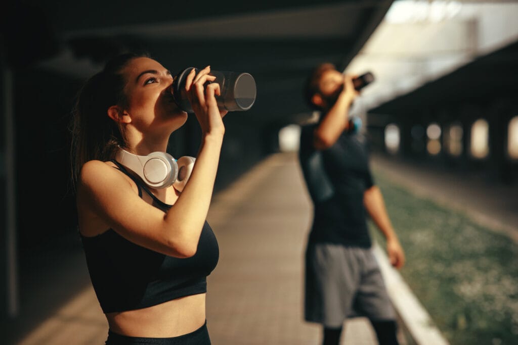 Young woman and man drinking protein shake after workout.